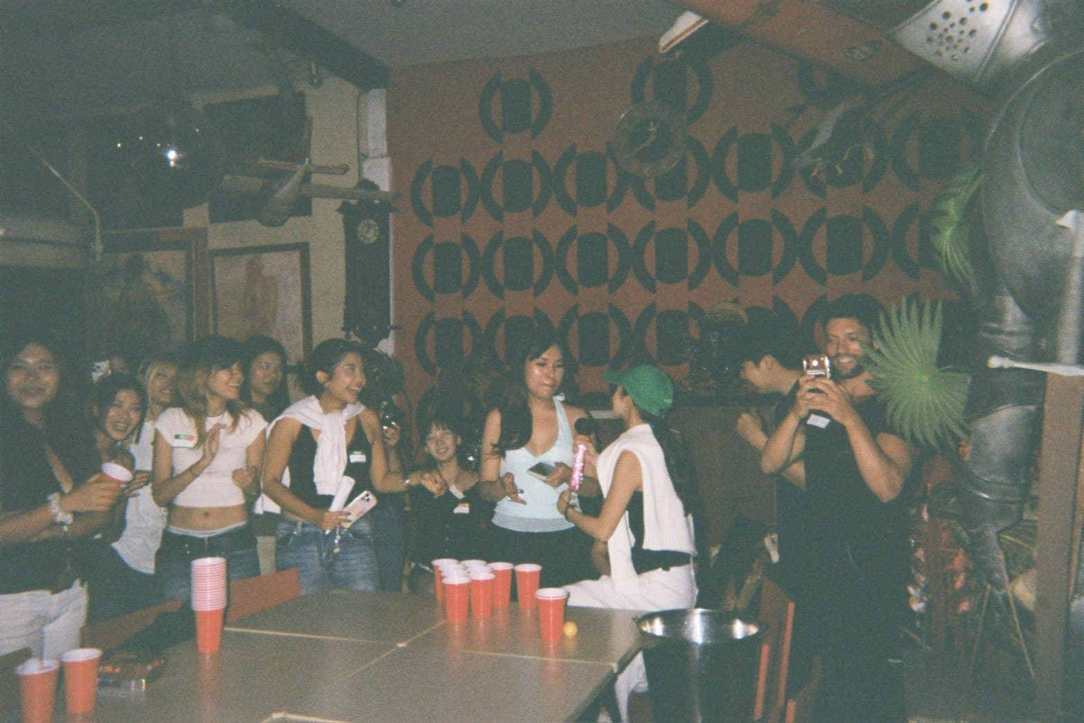 ผู้ร่วมงานยืนล้อมโต๊ะเล่นเกมในงาน Game Night