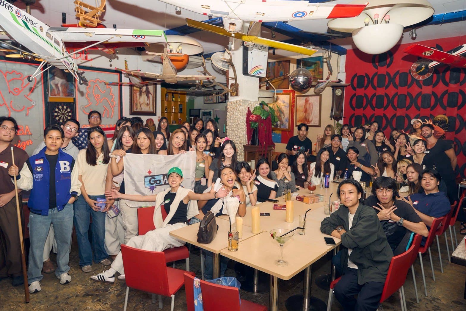ภาพหมู่ผู้ร่วมงานเต็มร้านถือธง GoWAT
