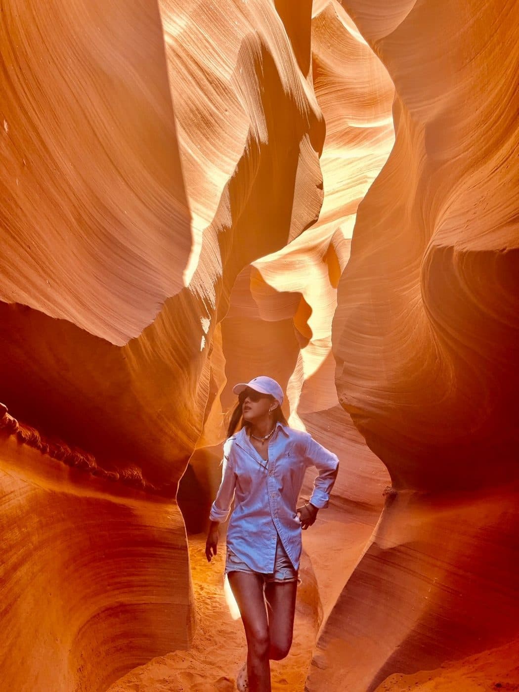จิลยืนอยู่ในหุบเขา Antelope Canyon รัฐแอริโซนา ผนังหินสีส้มโค้งรอบตัว